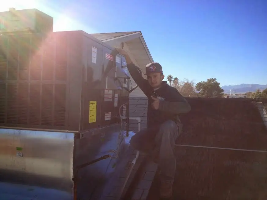 HVAC technician performing HVAC Inspection on a rooftop unit in Mendon